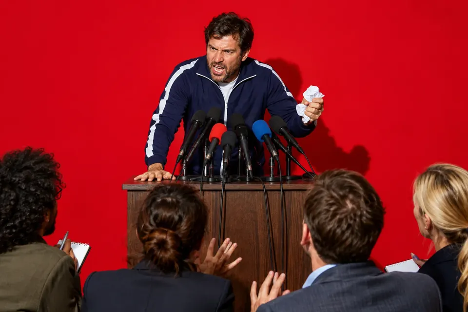 Leidenschaftlicher Fußballtrainer schlägt bei einer Pressekonferenz vor vielen Mikrofonen auf den Tisch
